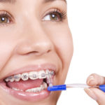 happy girl with braces brushing her teeth